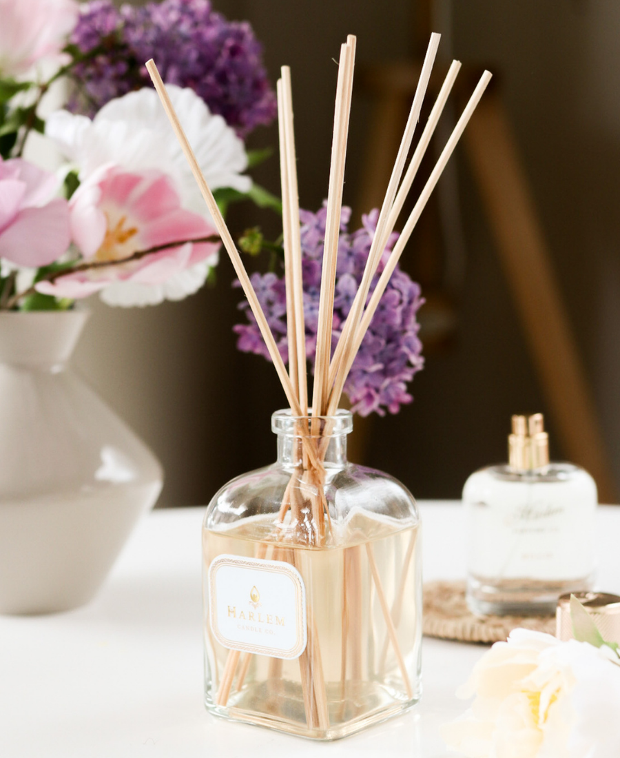 Dream Reed Diffuser on a white table with flowers and the Billie Perfume.