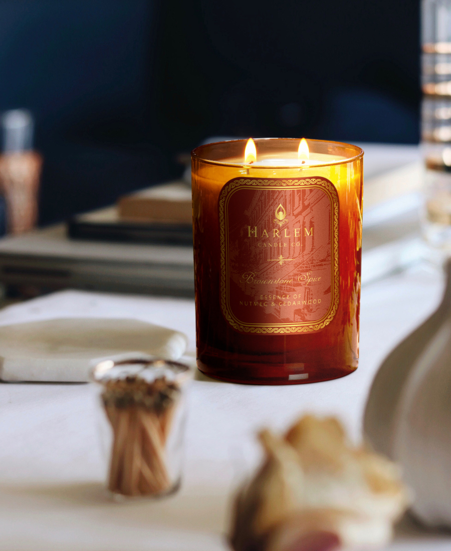 Brownstone Spice Candle on a white desk with matches, books, flowers, and ceramics.