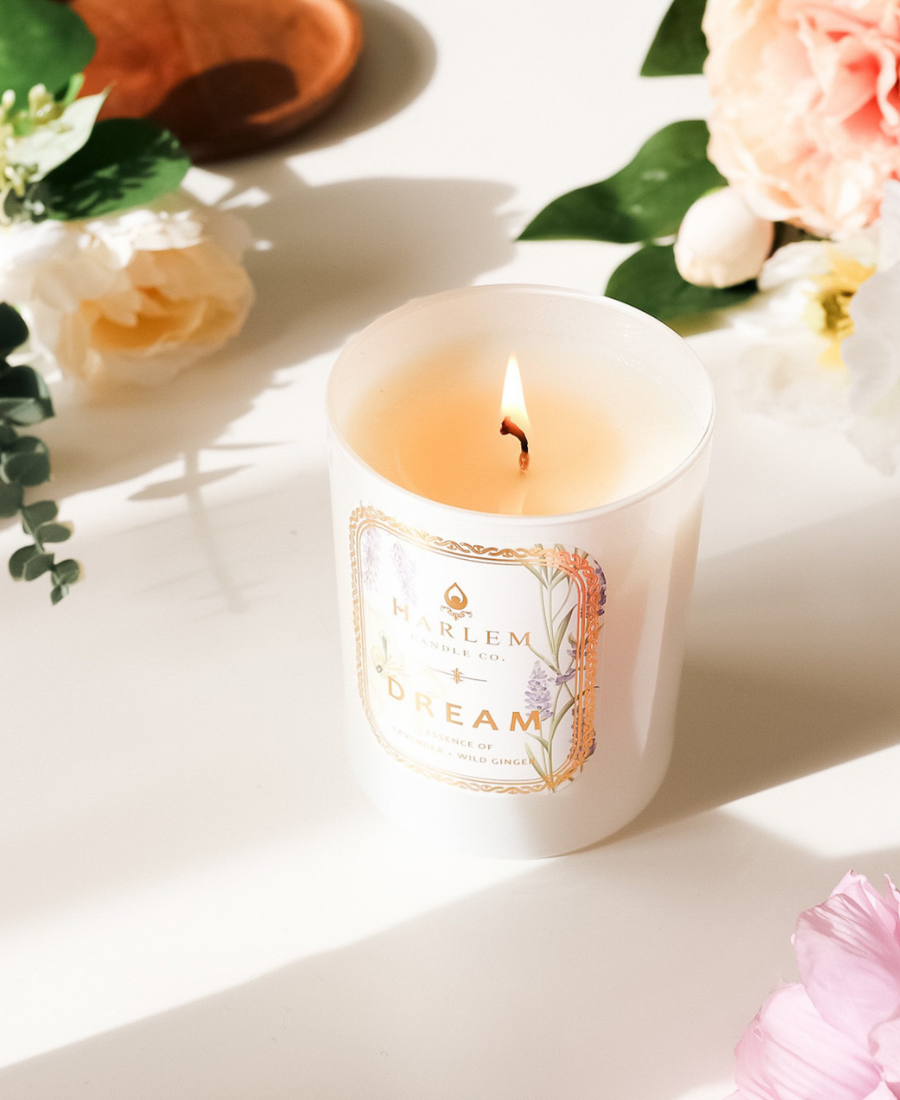 Dream Candle on a white table with flowers.