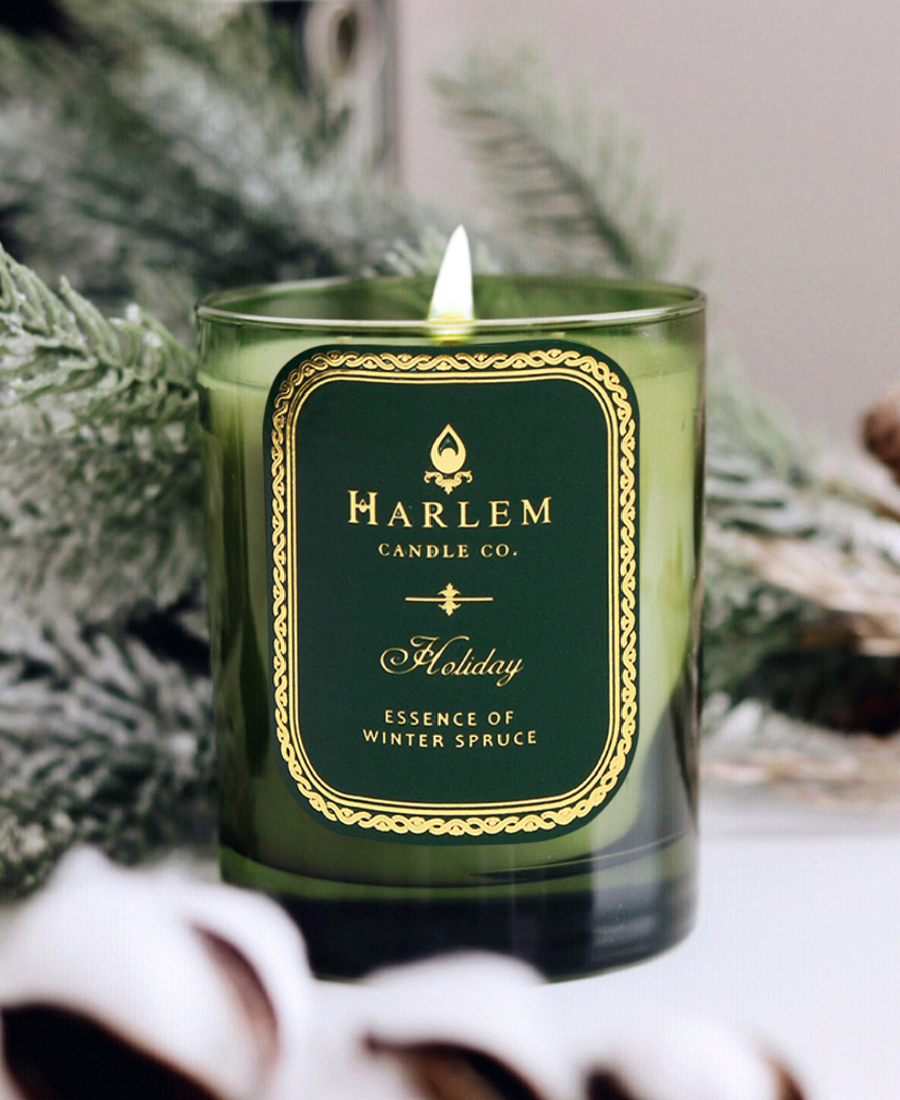 Holiday Candle on a white table with frosted greenery.