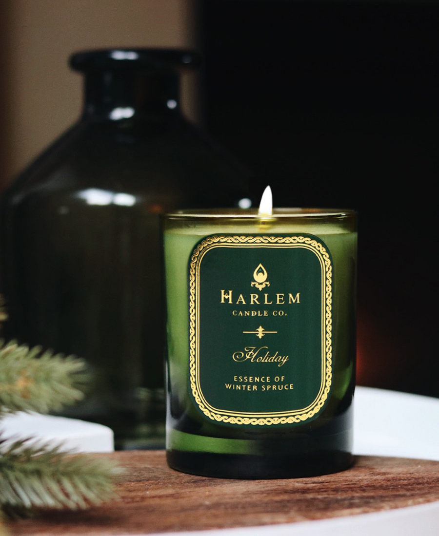 Holiday Candle on a wooden tray with greenery and a green vase.