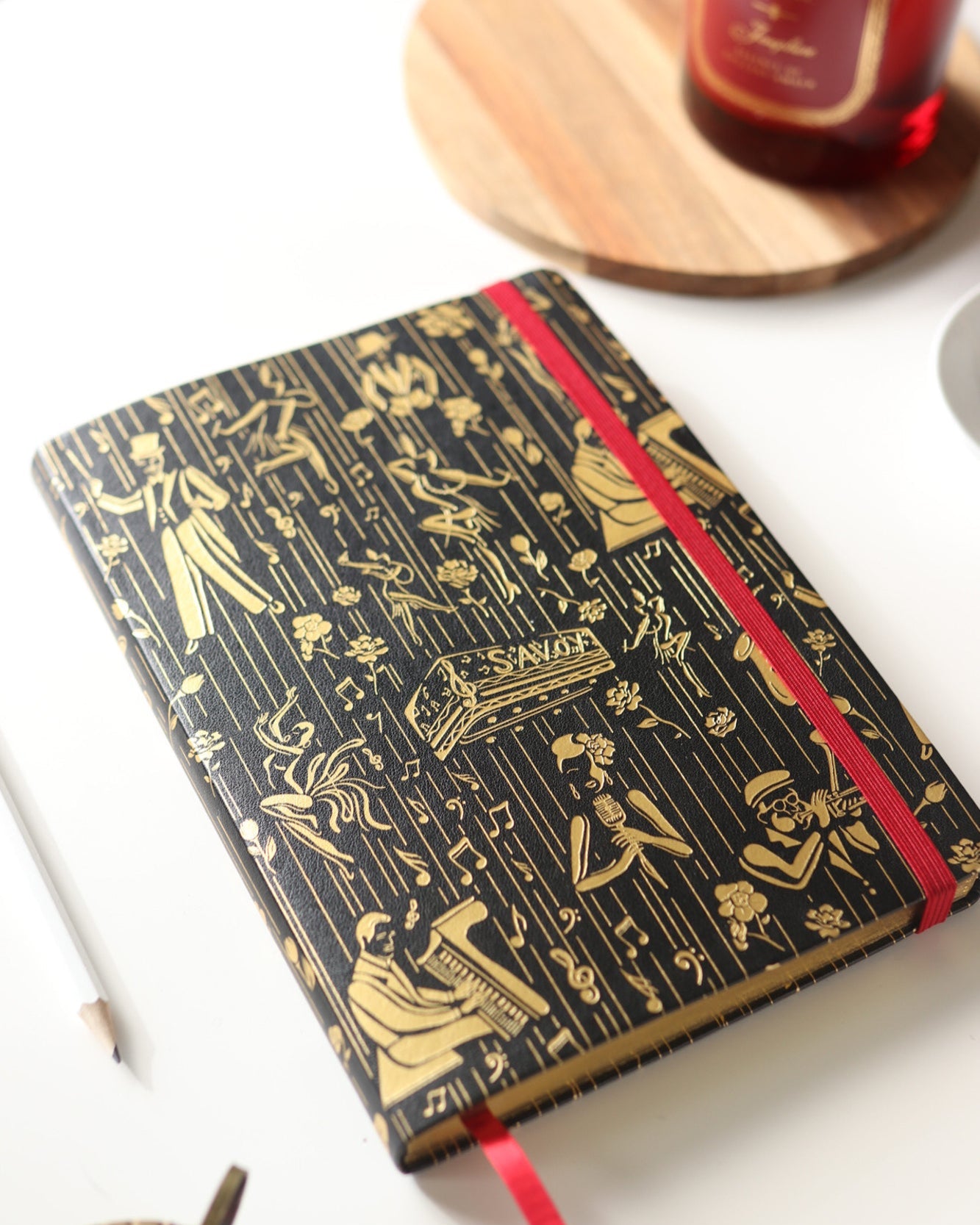 This is a lifestyle image of the black and gold owed to the Harlem Renaissance journal that features illustrations of Billie Holiday, Duke Ellington, dizzy, Gillespie, and Cab Calloway.