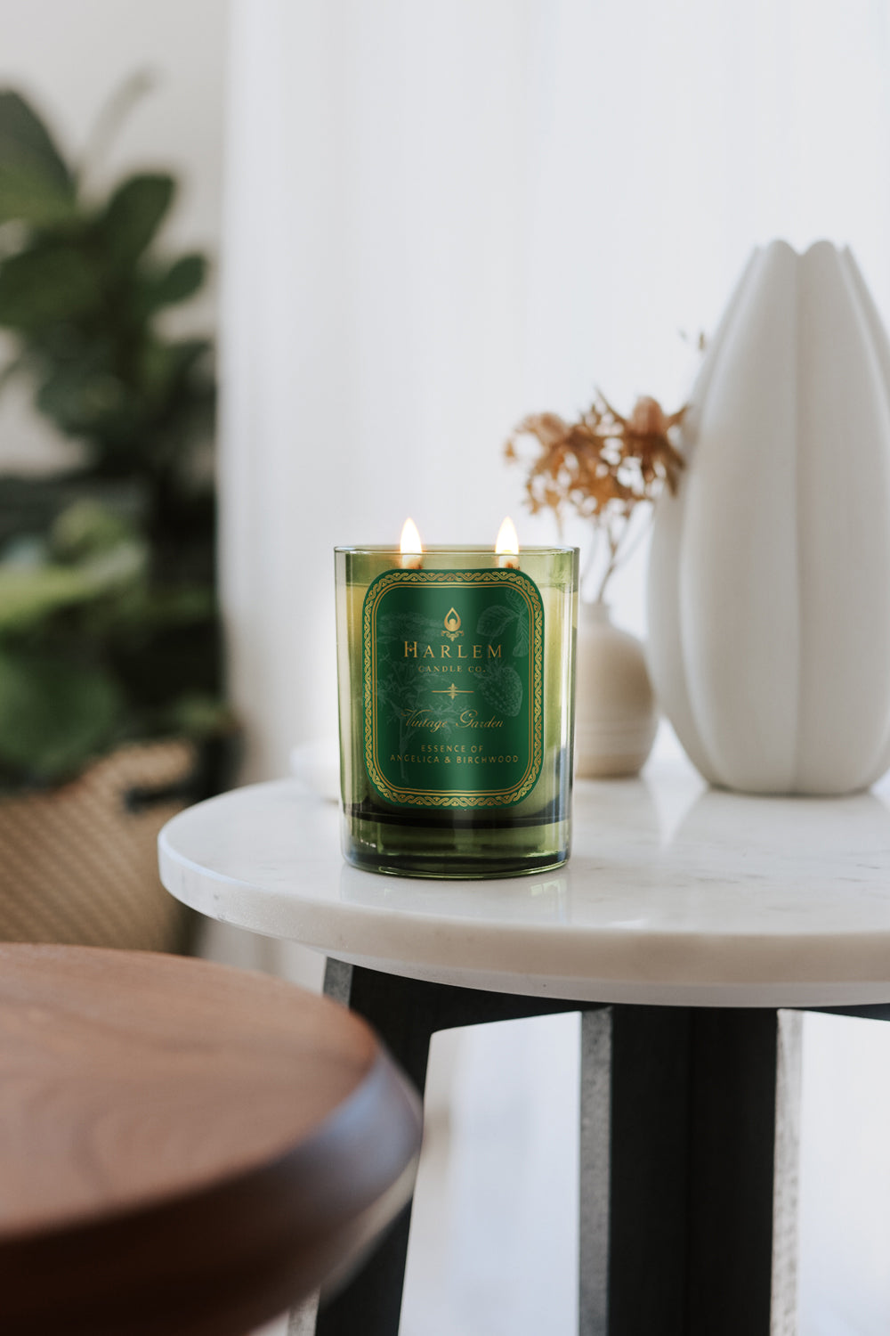 This is a lifestyle image of our vintage garden candle on a white marble table next to ceramic white vases.