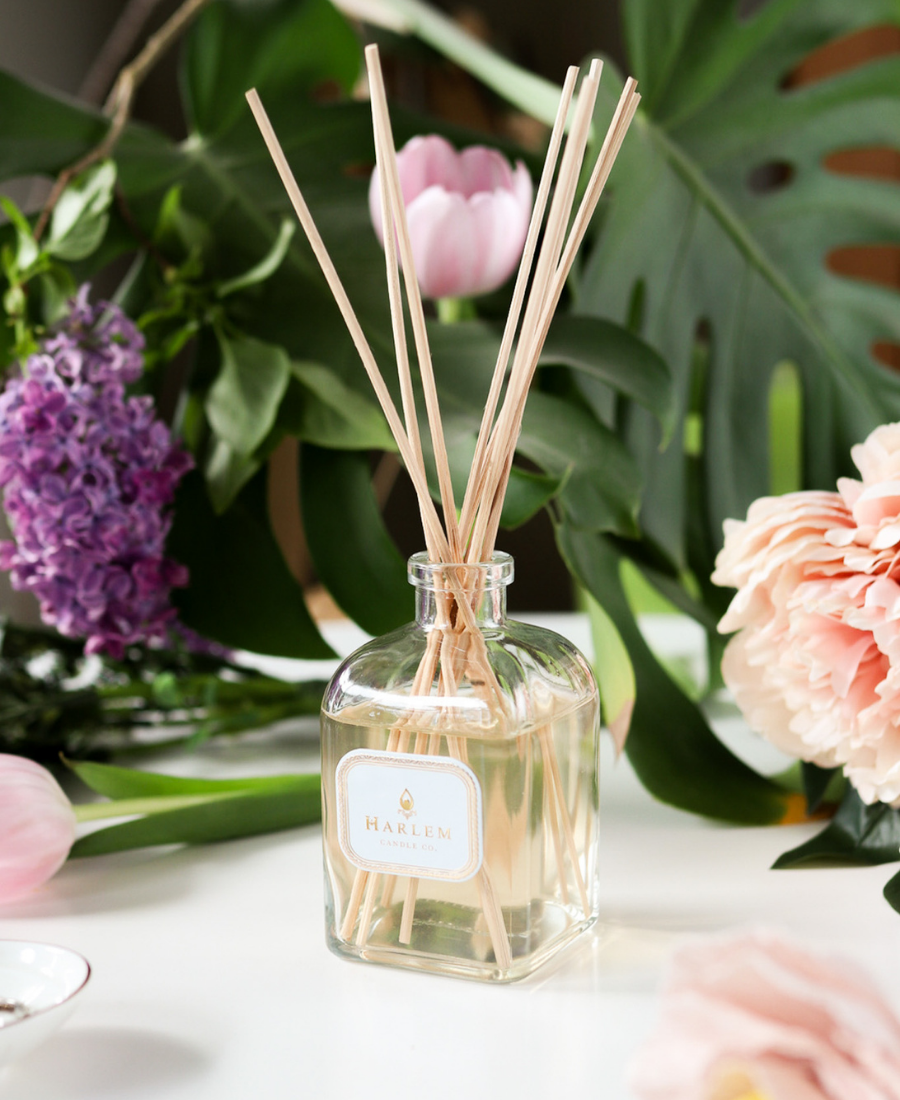 Home Reed Diffuser on a white table with flowers.