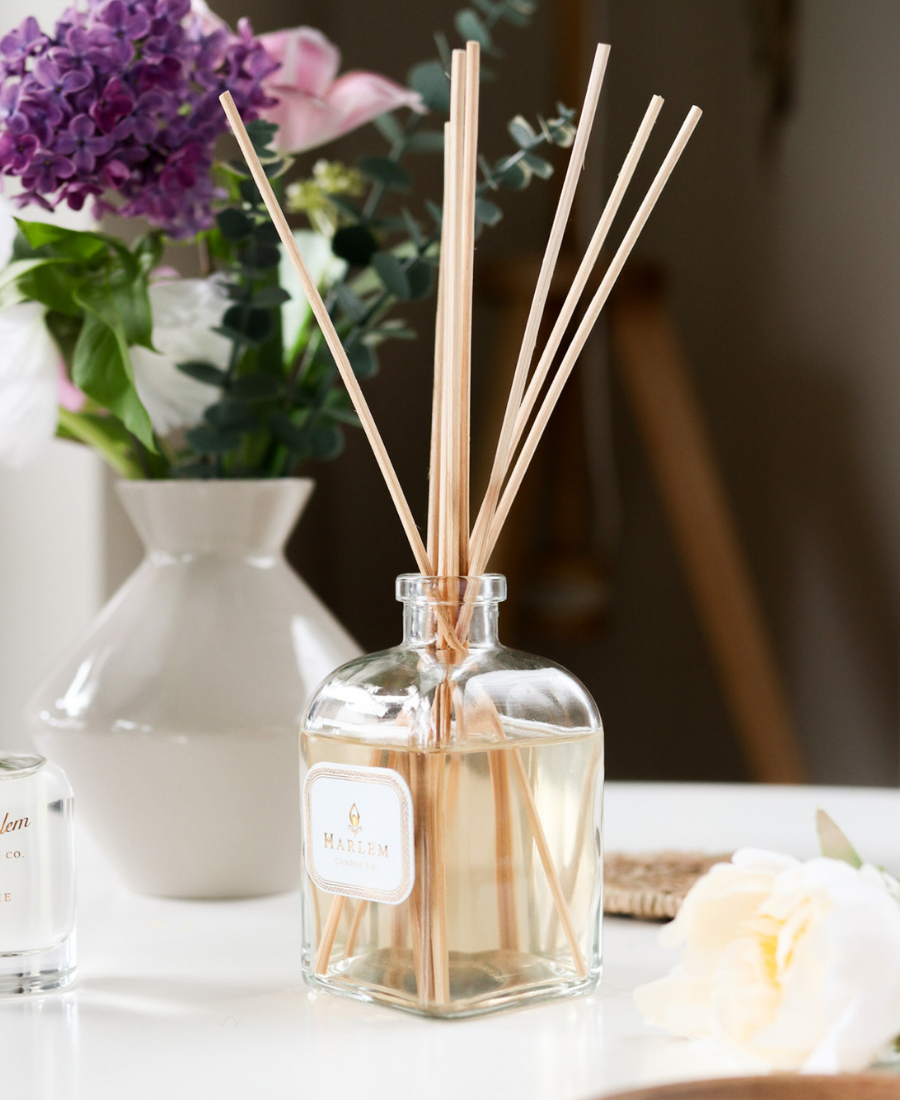 Bloom Reed Diffuser on a white table with flowers.