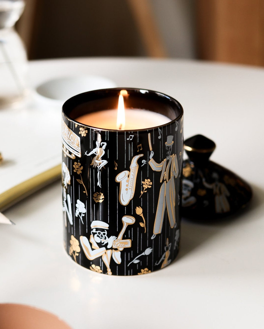 This is a lifestyle image of our Duke ceramic candle featuting illustrations of Dizzy Gillespe, Cab Calloway, and other symbols of jazz.