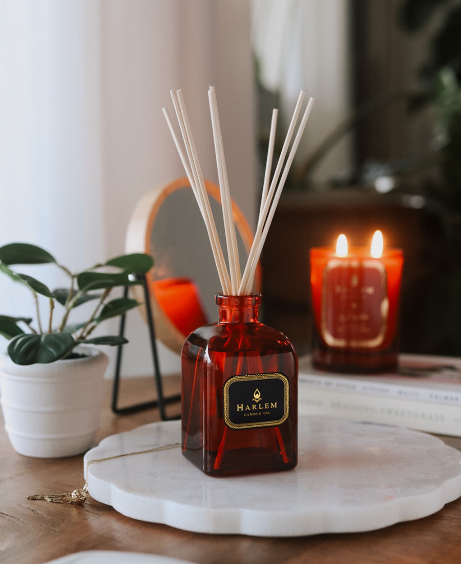 Josephine Reed Diffuser on a marble tray with a potted plant, mirror, jewelry, books, and the Josephine Candle