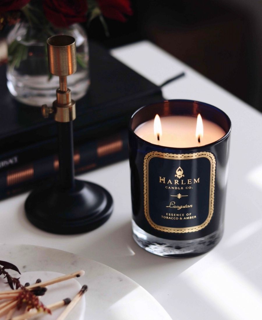 Langston Candle on a white table with books, a candle holder, and matches.