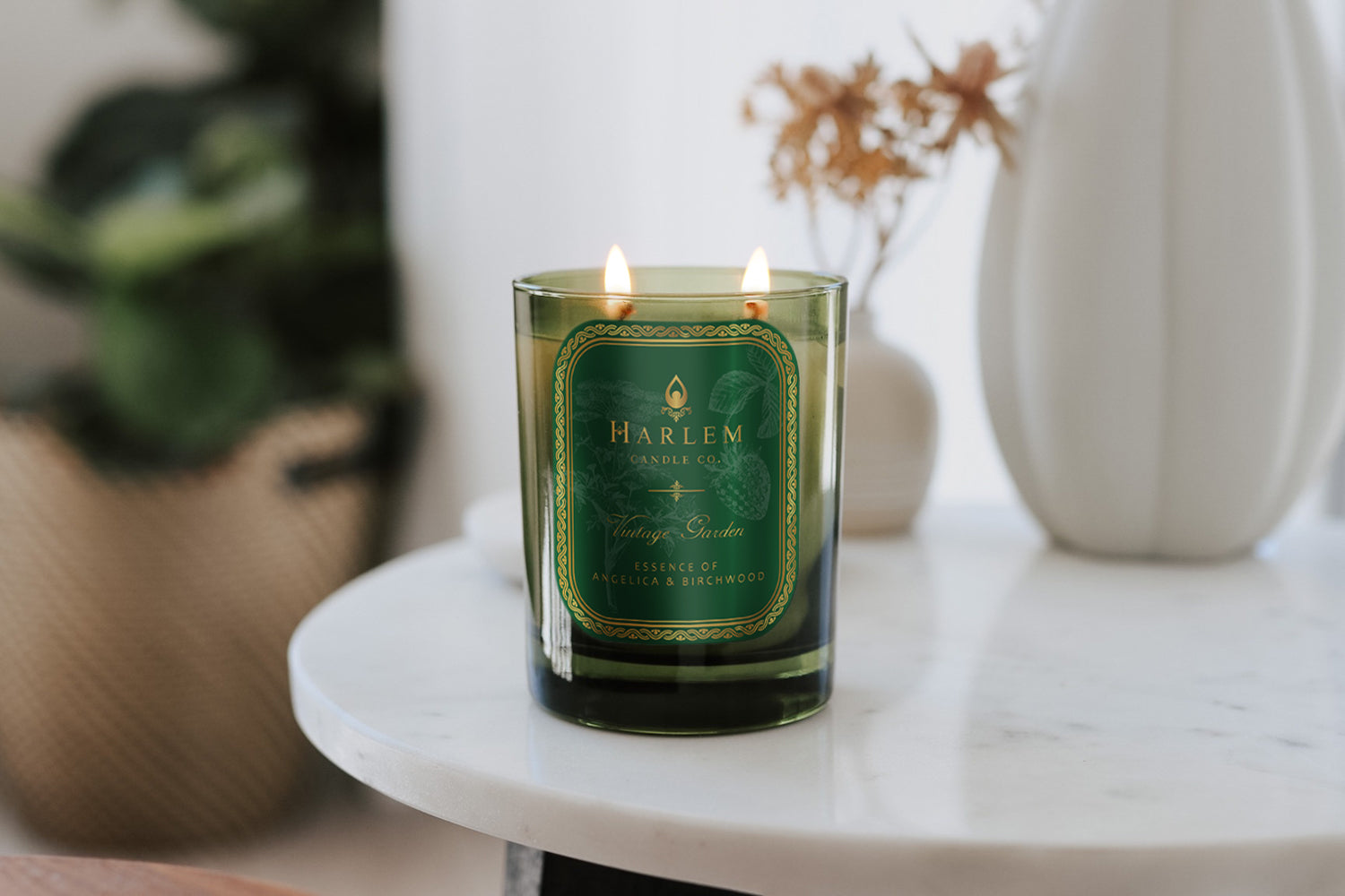 This is a lifestyle image of our vintage garden candle on a white marble table next to ceramic white vases.