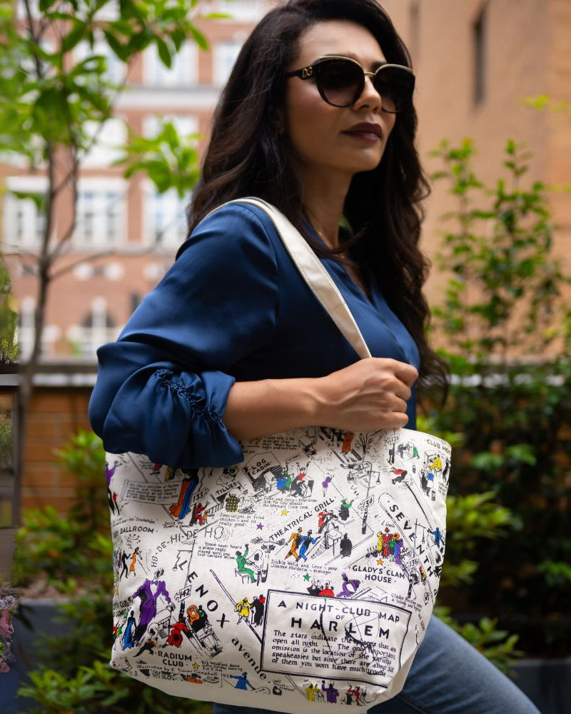 Woman holding a tote bag with a colorful design in an outdoor setting