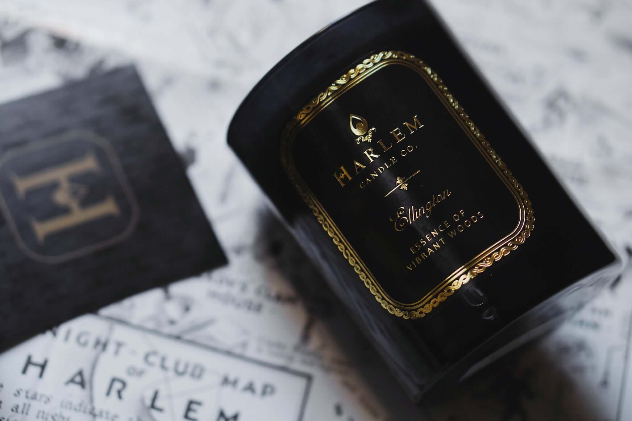 Our Ellington 12 oz black candle laying on its side on top of our Night Club Map of Harlem.